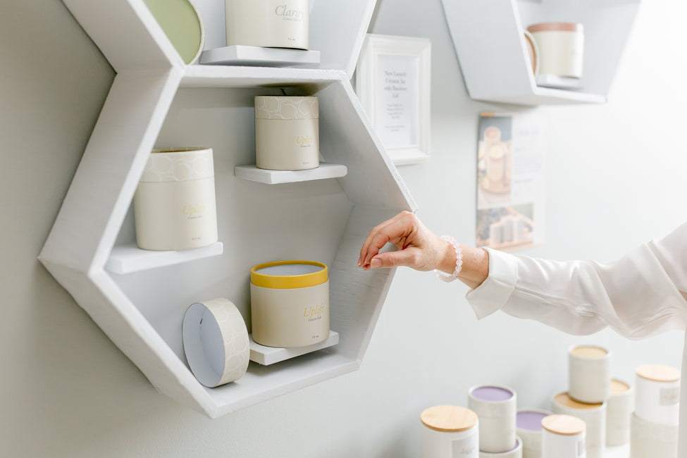 Lisa reaching for her Green Ash candles that are displayed on the wall on a honeycomb shaped shelf 